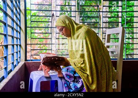 A village Muslim woman reads the Al Quran at morning in her home in Jamalpur District, Bangladesh, on October 01, 2020 Stock Photo