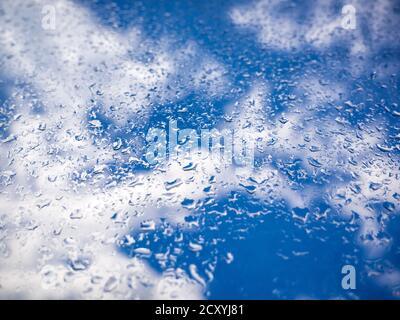 Rain drops on the window glass. Blurred background with clouds and blue sky - selective focus Stock Photo