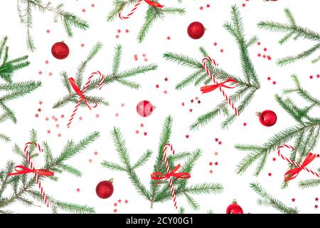 Christmas pattern of fir tree branches and red decoration with candy cane on white. Flat lay Stock Photo