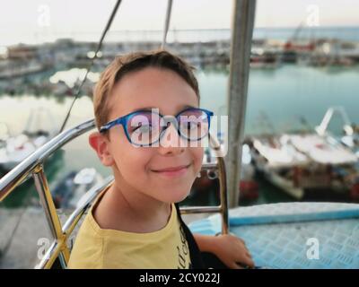 beautiful boy with yellow shirt and glasses posing on ferris wheel  Stock Photo