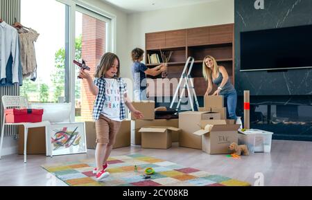 Boy playing with toy airplane while parents unpack Stock Photo