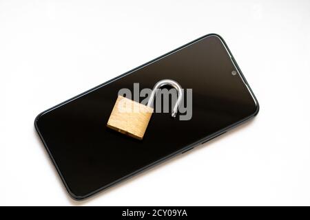 Vulnerable encryption and cyber security shows an open key lock on a black smartphone for hacker attack or cyber attack protection as safety business Stock Photo
