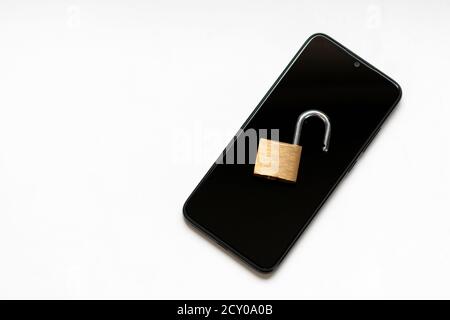 Vulnerable encryption and cyber security shows an open key lock on a black smartphone for hacker attack or cyber attack protection as safety business Stock Photo