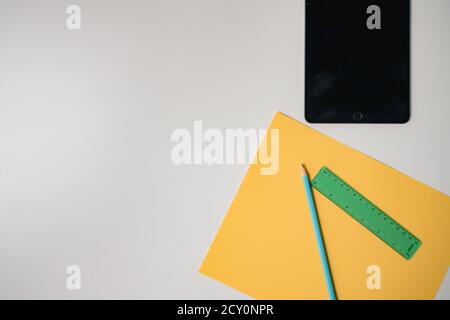 black tablet and school supplies on plain white table Stock Photo