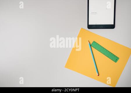virtual learning tablet and school supplies on plain white background Stock Photo