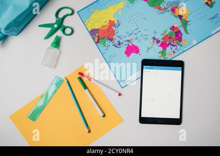 Home school supplies on white background with tablet and map Stock Photo