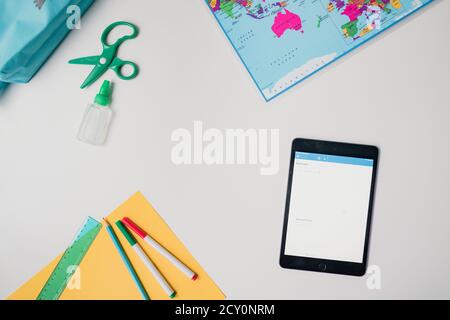 distance learning materials with tablet, map, markers, scissors, glue Stock Photo