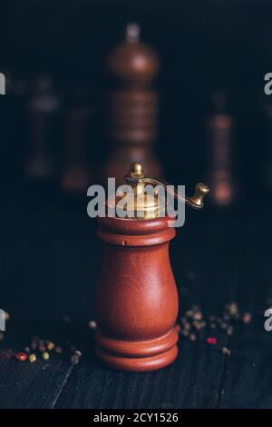 Pepper or coffee vintage wooden grinder on a dark black background. Stock Photo