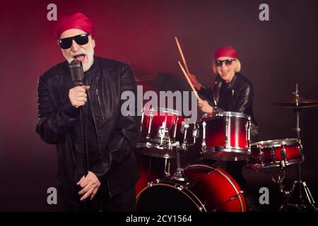 Photo of pensioners lady man popular rock group couple play drum instrument sing famous song concert performance wear rocker leather clothes bandana Stock Photo