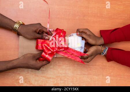 two people holding on to an envelope containing money Stock Photo