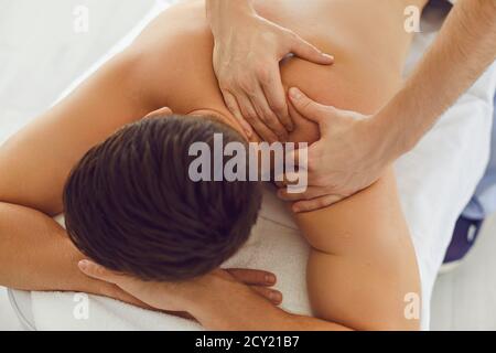 Relaxed young male client getting professional remedial body massage in spa salon Stock Photo