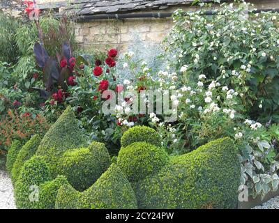 Topiary chickens and colourful planting in the courtyard of the award-winning Cotswolds gardens at Bourton House, as featured on Gardeners' World. Stock Photo