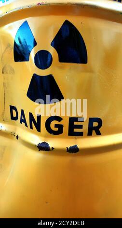 Distorted caution symbol of nuclear threat on yellow painted rusty metal barrel with damaged surface Stock Photo