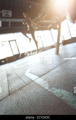 Sport training concept. Vertical shot of athletic woman in sportswear working out at industrial gym, focus on the floor. Wellness and healthy lifestyle Stock Photo