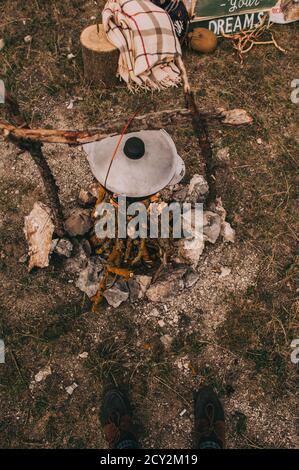 Cauldron for cooking hangs over a campfire for camping outdoors in the woods. Top view. Stock Photo