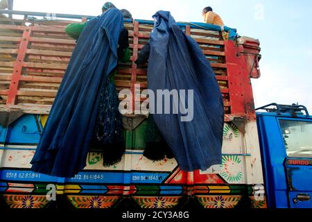 Afghan refugee women, clad in a burqa, climb on a truck to be repatriated to Afghanistan, at the United Nations High Commissioner for Refugees (UNHCR) office on the outskirts of Peshawar February 13, 2015. Afghan immigrants ordered out of Pakistan in what officials say is a bid to root out militants are, some analysts say, scapegoats being used to distract attention from the authorities' failure to end violence. Thousands of Afghans unnerved by threats of arrest and growing hostility towards them have flocked out of Pakistan back home, leaving behind boarded-up shops, houses and restaurants. P