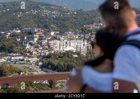 a young couple looks down from a observation deck on a district of the Sochi city in Krasnodar Krai, Russia Stock Photo