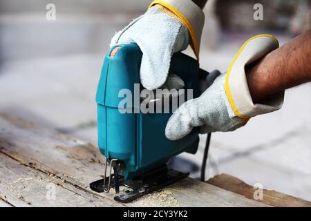 Carpenter with fretsaw at outdoor work. close-up. Construction details of male worker or handy man with power tools. Stock Photo