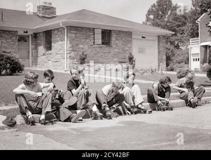 1950s GROUP OF SEVEN SUBURBAN PRETEENS BOYS AND GIRLS SITTING ON STREET CURB TOGETHER PUTTING ON ADJUSTING METAL ROLLER SKATES  - j4989 HAR001 HARS JOY LIFESTYLE FEMALES HOUSES BROTHERS HOME LIFE COPY SPACE FRIENDSHIP HALF-LENGTH RESIDENTIAL MALES BUILDINGS SIBLINGS SISTERS B&W NEIGHBORS ACTIVITY PHYSICAL NEIGHBORHOOD HIGH ANGLE ADVENTURE LEISURE STRENGTH EXCITEMENT EXTERIOR RECREATION SEVEN HOMES SIBLING CONCEPTUAL 7 FLEXIBILITY FRIENDLY MUSCLES RESIDENCE CURB COOPERATION JUVENILES PRE-TEEN PRE-TEEN BOY PRE-TEEN GIRL ROLLER SKATES SKATERS TOGETHERNESS BLACK AND WHITE CAUCASIAN ETHNICITY Stock Photo