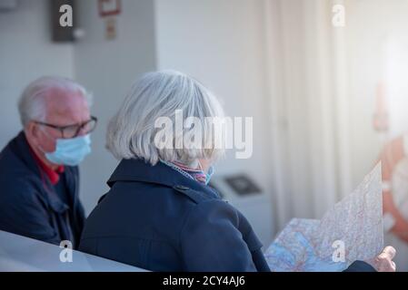 Tourist senior couple with face masks looking on map Stock Photo