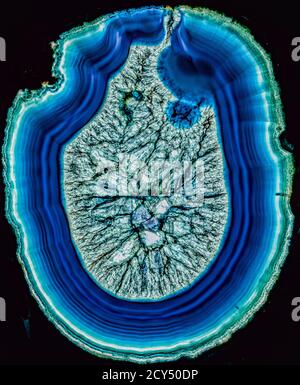Concept of a volcano breaking through the surface slice of blue agate through polarized light Stock Photo