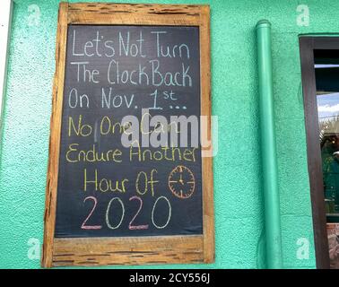 A funny chalkboard sign outside of a restaurant that says, 'Let's not turn the clock back on November 1st.  No one can endure another hour of 2020'. Stock Photo