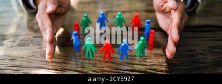 African Man Protecting Employee Figures With Hand Stock Photo