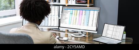 African American Analyzing Spreadsheet Data At Work Stock Photo