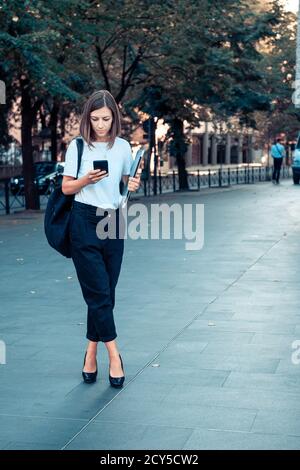 Business woman with laptop and smart phone in hands on city street. Stock Photo