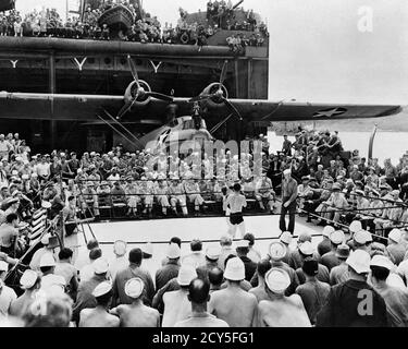 1940s US NAVY SAILORS AND OFFICERS WATCHING A BOXING MATCH BOUT ABOARD WW2 AIRCRAFT CARRIER PBY CATALINA FLYING BOAT IN B/G - n431 HAR001 HARS CATALINA MIDDLE-AGED B&W MIDDLE-AGED MAN WIDE ANGLE HIGH ANGLE STRENGTH VICTORY COURAGE AND EXCITEMENT LEADERSHIP POWERFUL RECREATION PRIDE A IN AUTHORITY OCCUPATIONS SAILORS UNIFORMS CONCEPTUAL OFFICERS USN BOUT MID-ADULT MID-ADULT MAN RELAXATION TOGETHERNESS YOUNG ADULT MAN ABOARD AMPHIBIOUS BLACK AND WHITE HAR001 OLD FASHIONED Stock Photo