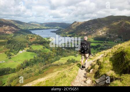 walker descending from St Sunday Crag walking towards Ullswater, Patterdale and Glenridding, Lake District, Cumbria, England, UK Stock Photo