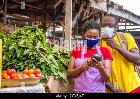 young black man spying on a lady using a pos machine Stock Photo