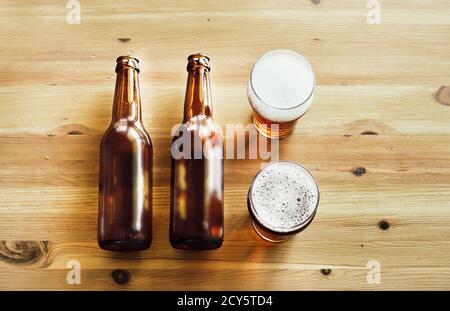 Two empty beer bottles and two glasses with beer on a wooden background, copy space, top view Stock Photo