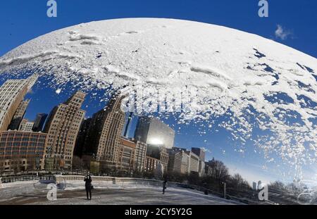 A woman and the Chicago skyline are reflected in the snow covered, curved surface of the 'Cloud Gate' sculpture in Chicago, Illinois, January 6, 2015. A bitter cold snap is freezing most of the eastern half of the United States, driving the mercury below zero in the Midwest on Monday, with possible freezing temperatures as far south as Atlanta later this week, forecasters said.  REUTERS/Jim Young  (UNITED STATES - Tags: ENVIRONMENT SOCIETY TPX IMAGES OF THE DAY)