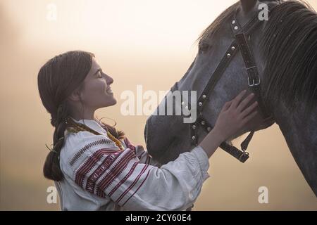 Young attractive woman in noble clothes stroking a horse. Stock Photo