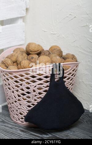 A basket with walnuts. She is wearing a medical mask. Nearby is a white wooden box. Stock Photo