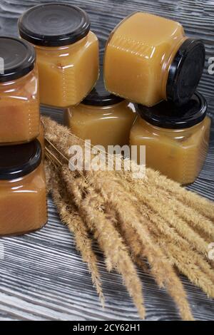 Jam in jars. Nearby is a bouquet of dry grass with spikelets. On black pine boards. Stock Photo