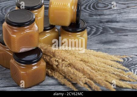 Jam in jars. Nearby is a bouquet of dry grass with spikelets. On black pine boards. Stock Photo