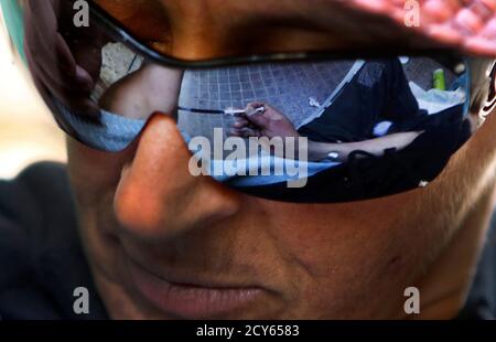 Vicky, a 40-year-old, Canadian-born, Greek drug addict, injects (reflection on her sunglasses)  herself with a cocktail known as speedball, a cocaine and heroin mix, on a central Athens sidestreet April 30, 2012. The WHO (World Health Organization) recommends that 200 clean syringes are provided per drug user per year to limit HIV infection. Greece has been providing three, the Hellenic Centre for Infectious Diseases Control says. Greece's financial crisis has resulted in a drop in its health spending by 36 percent last year, according to the National School of Public Health. In the first five