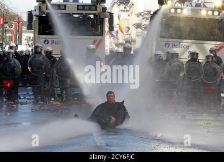 A demonstrator falls after getting sprayed by water canons as he tries to face the riot police during a protest by European workers and trade union representatives to demand better job protection in the European Union countries in Brussels March 24, 2011. Tens of thousands of people marched through Brussels on Thursday to urge European leaders holding a two-day summit in the Belgian capital to scrap or ease austerity measures, which unions say will slow economic recovery and punish the poor. REUTERS/Thierry Roge (BELGIUM - Tags: POLITICS CIVIL UNREST BUSINESS)