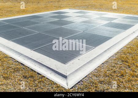 Wide-angle view of a huge rectangular air shaft outdoors leading to metro or an underground facility with a striped square metal grills on the top put Stock Photo