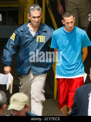 An FBI agent escorts one of the police officers and prison guards arrested in a major anti-corruption operation across the U.S. Caribbean territory out of the Puerto Rico Federal Court Building in San Juan, October 6, 2010. REUTERS/Ana Martinez (PUERTO RICO - Tags: POLITICS CRIME LAW)