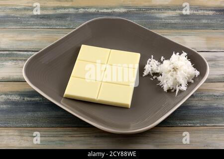 White chocolate candy bar with coconut buts and shredded sweet coconut on candy dish Stock Photo