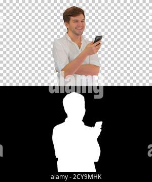 Handsome young man using his smartphone and laughing, Alpha Chan Stock Photo