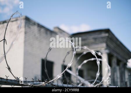 Razor wire or barbed wire on top of security fence or fencing to protect property in Montgomery Alabama, USA. Stock Photo