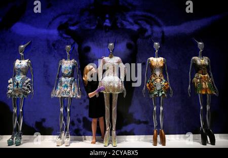 A staff member poses with dresses from the Alexander McQueen Plato's  Atlantis spring/summer 2010 collection