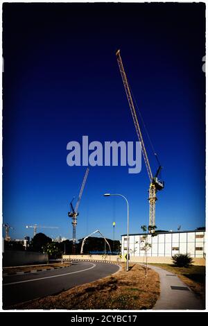 Vertical view. Artistic scene of construction tower cranes against the deep blue hue. Singapore. Stock Photo