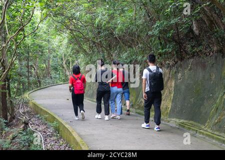 young men, women or boys and girls, university students with face masks hiking along trails in Victoria Peak, Hong Kong during covid-19 Stock Photo