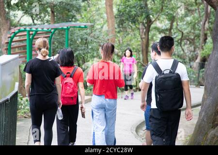 young men, women or boys and girls, university students with face masks hiking along trails in Victoria Peak, Hong Kong during covid-19 Stock Photo