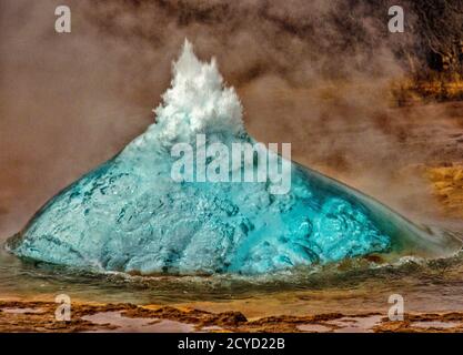 Geyser in Iceland begins eruption by first forming a bubble of hot water, before bursting into the air Stock Photo